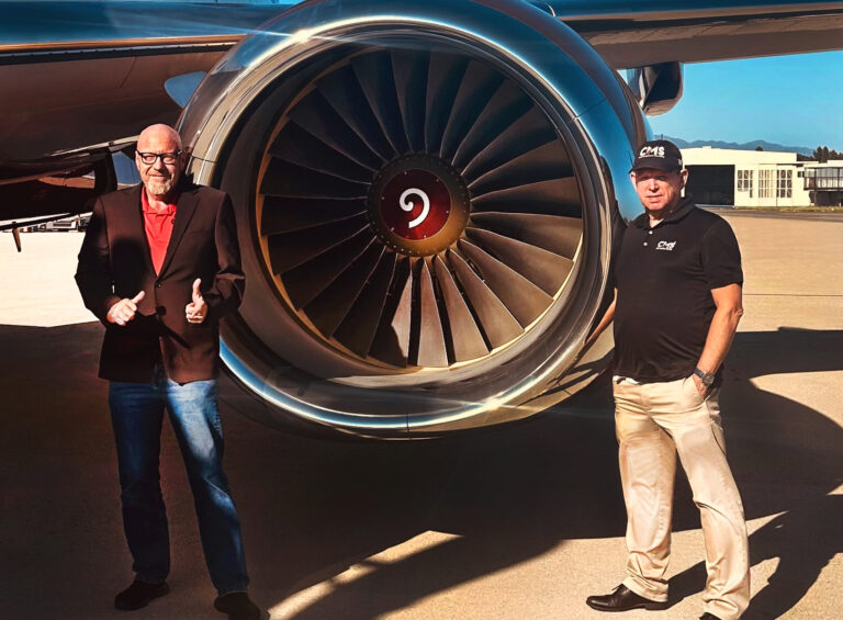 Plane wing and engine with 2 men standing on either side of engine